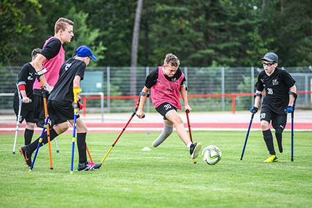Beitragsbild Junior Camp 2020 abgesagt, 5 jugendliche Amputierten Fußballer beim Spiel auf einem Rasenplatz