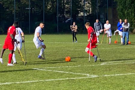 Zwei amputierte Fußballer auf Krücken im Zweikampf um den Ball auf Rasen