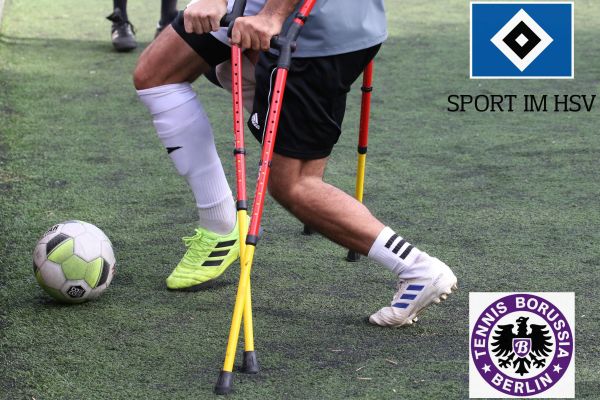 Zwei amputierte Fußballer auf Krücken im Zweikampf um den Ball auf Kunstrasen.